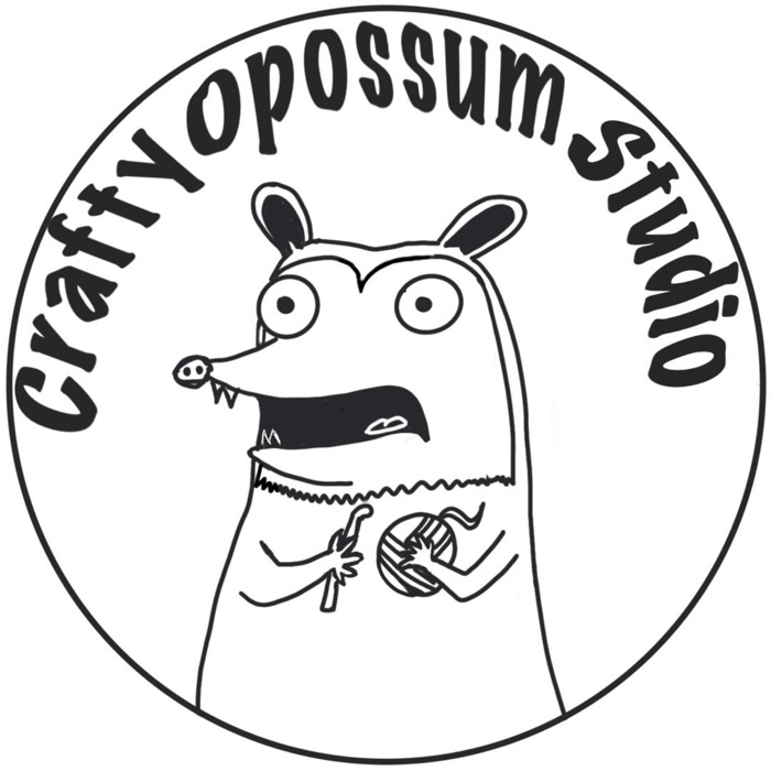 Crafty Opossum Studio: a hand-drawn opossum with wide eyes, crocheting with a ball of yarn, inside a circular badge.